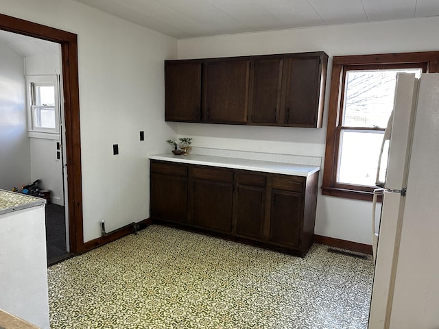 kitchen featuring dark brown cabinetry, white refrigerator, and a wealth of natural light