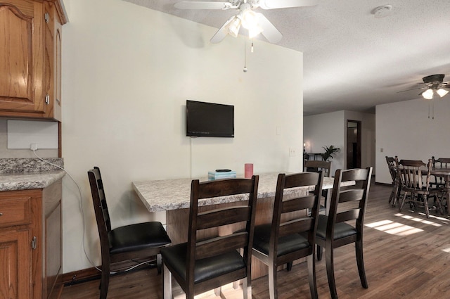 dining area with dark hardwood / wood-style floors, ceiling fan, and a textured ceiling