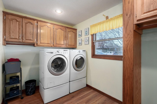 laundry area with washing machine and dryer, light hardwood / wood-style flooring, cabinets, and a textured ceiling