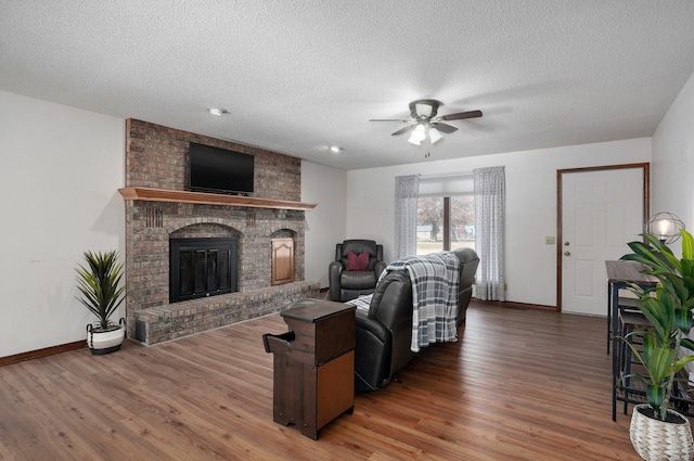 living room featuring a fireplace, hardwood / wood-style floors, a textured ceiling, and ceiling fan