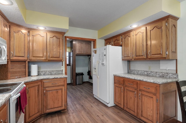 kitchen featuring a textured ceiling, light hardwood / wood-style floors, and white appliances