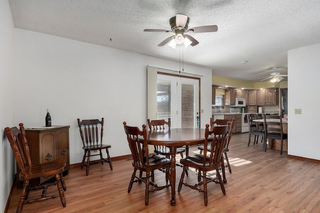 dining area with ceiling fan, french doors, a textured ceiling, and light wood-type flooring