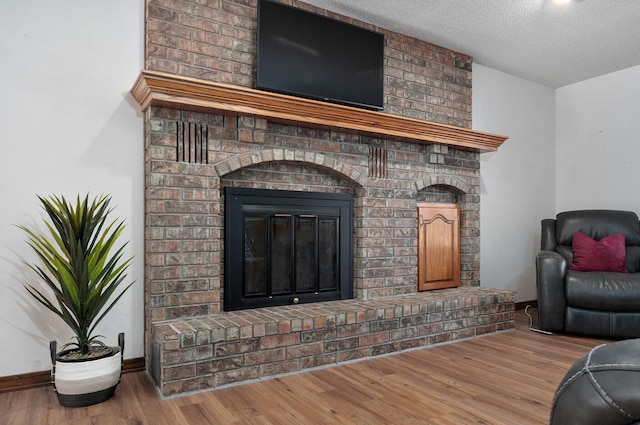 living room featuring a textured ceiling, wood-type flooring, and a fireplace