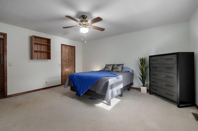 bedroom featuring a textured ceiling, light colored carpet, and ceiling fan