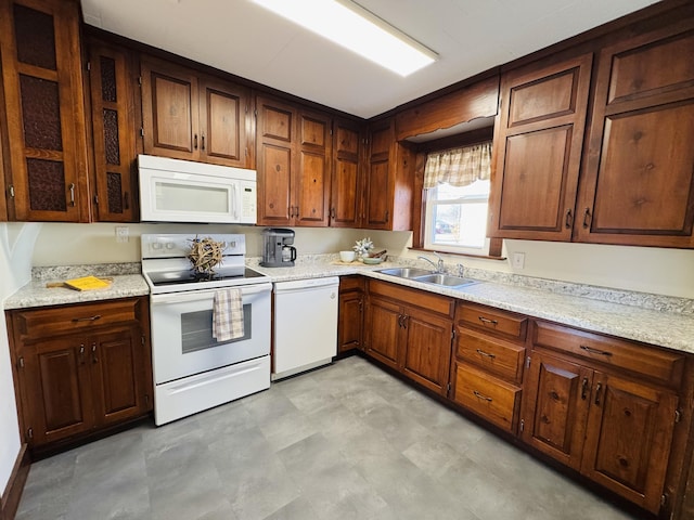 kitchen featuring light stone countertops, sink, and white appliances