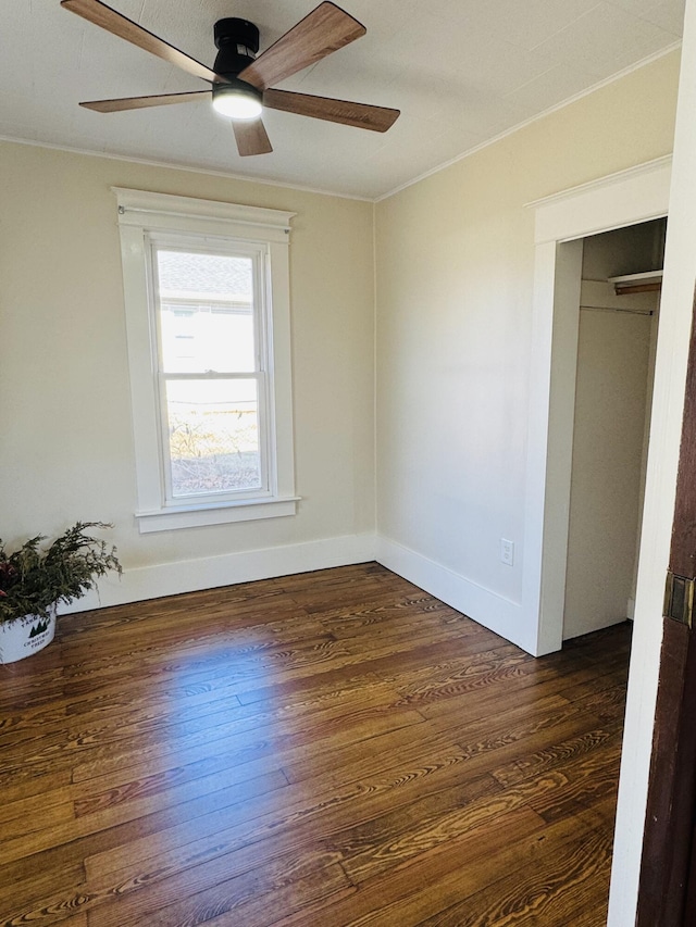 unfurnished bedroom with a closet, dark hardwood / wood-style floors, ceiling fan, and crown molding