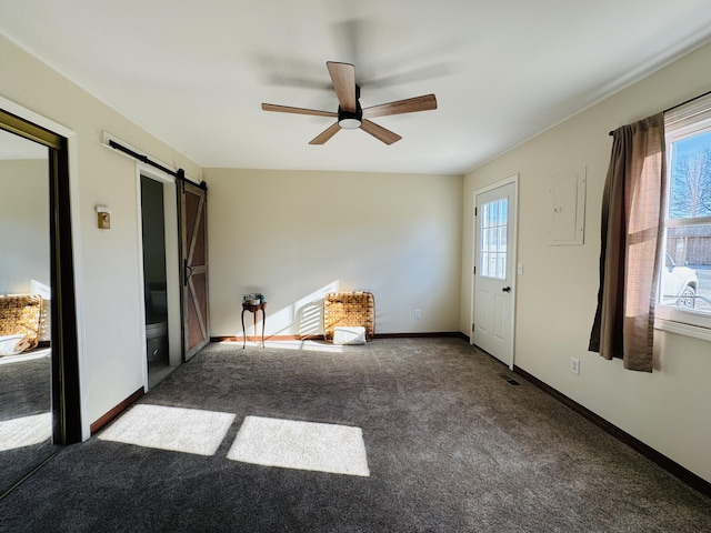 interior space featuring carpet flooring, ceiling fan, a barn door, and a wealth of natural light