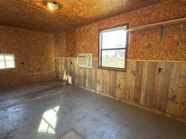 interior space with wooden walls, a wall unit AC, and concrete floors