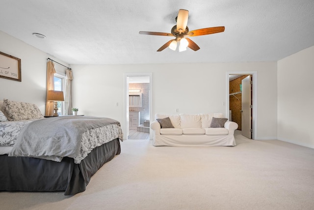 bedroom featuring connected bathroom, light colored carpet, a spacious closet, and ceiling fan