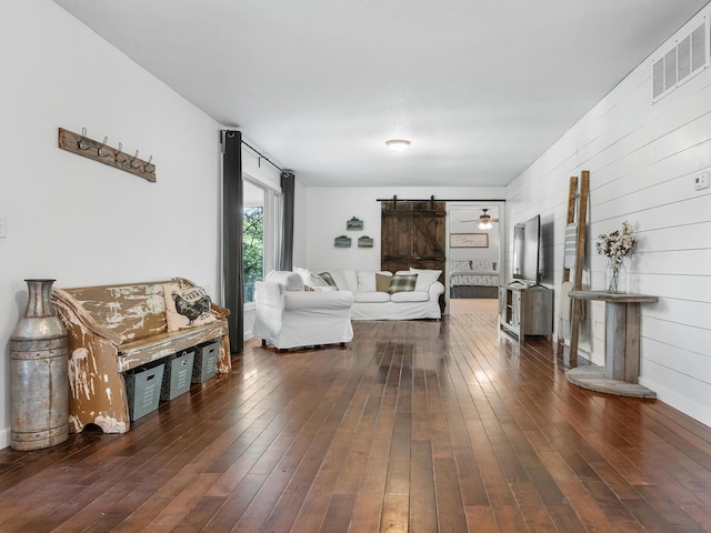 living room with a barn door and dark hardwood / wood-style flooring