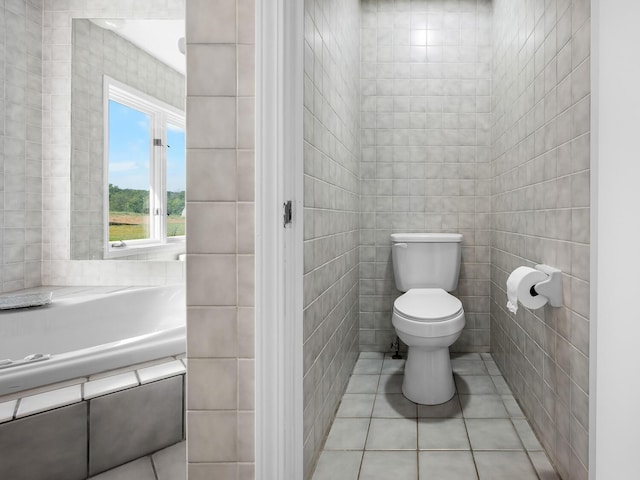 bathroom with tile patterned floors, toilet, tile walls, and tiled tub