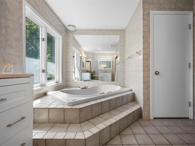 bathroom featuring tile patterned floors, vanity, tiled tub, and a wealth of natural light