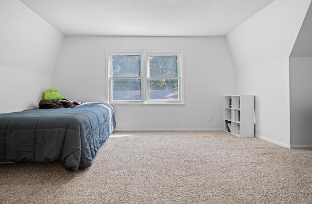 bedroom with a textured ceiling, carpet, and vaulted ceiling