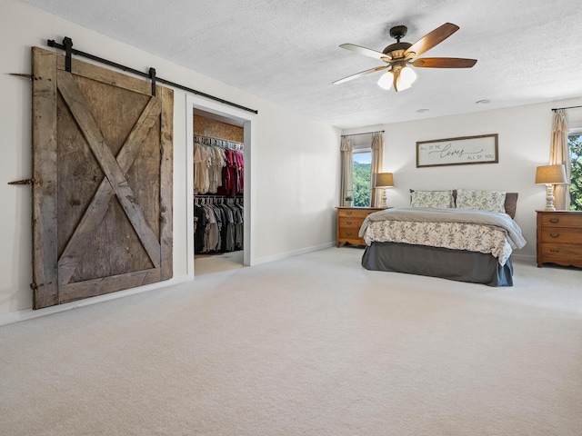 bedroom with light carpet, ceiling fan, a barn door, a textured ceiling, and a closet