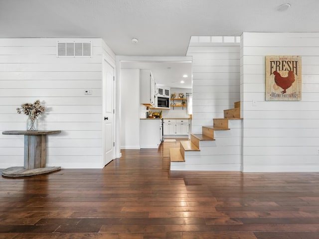 interior space featuring dark hardwood / wood-style flooring and wooden walls