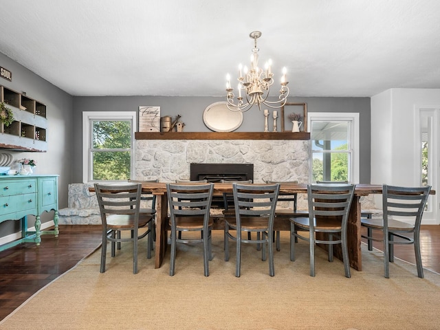 dining room featuring hardwood / wood-style flooring, a healthy amount of sunlight, a fireplace, and a chandelier