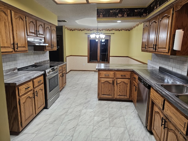 kitchen with sink, decorative backsplash, appliances with stainless steel finishes, decorative light fixtures, and kitchen peninsula