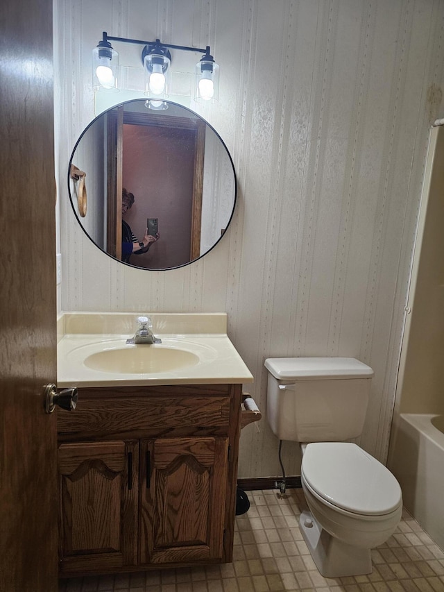 bathroom with tile patterned floors, a tub to relax in, vanity, and toilet