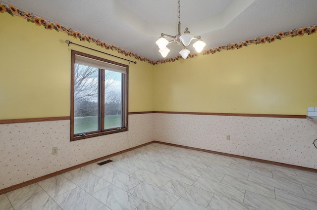 empty room with a tray ceiling and a chandelier