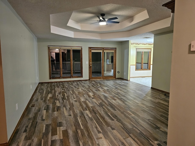 spare room featuring ceiling fan, dark hardwood / wood-style flooring, a raised ceiling, and a textured ceiling