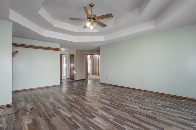 spare room with a raised ceiling, ceiling fan, and dark hardwood / wood-style floors