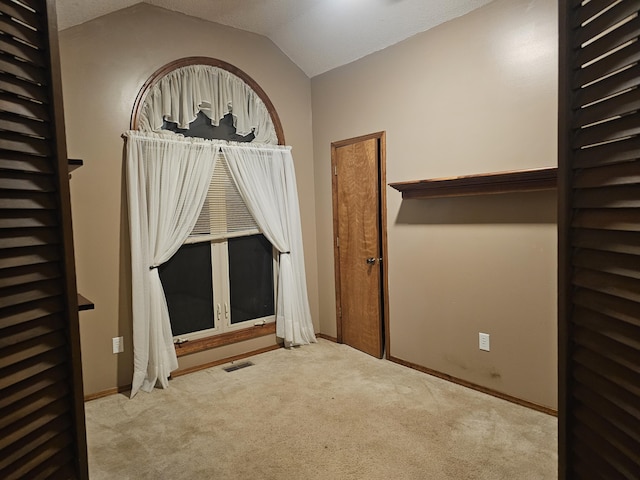 interior space featuring light colored carpet and vaulted ceiling