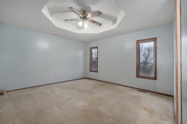 carpeted spare room featuring a textured ceiling, a raised ceiling, and ceiling fan