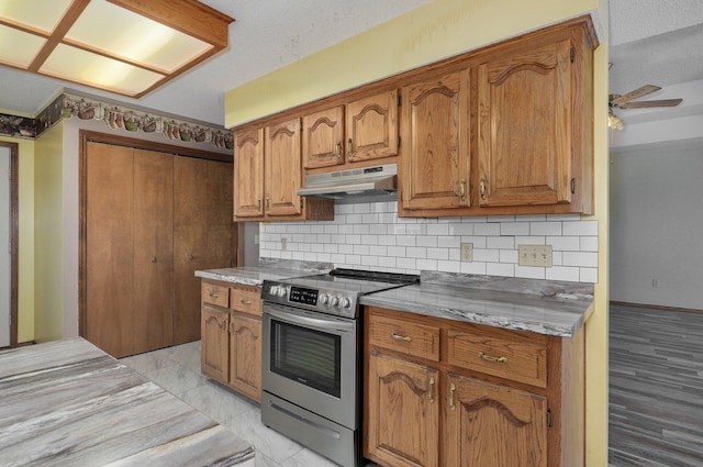 kitchen with a textured ceiling, backsplash, ceiling fan, and stainless steel range oven