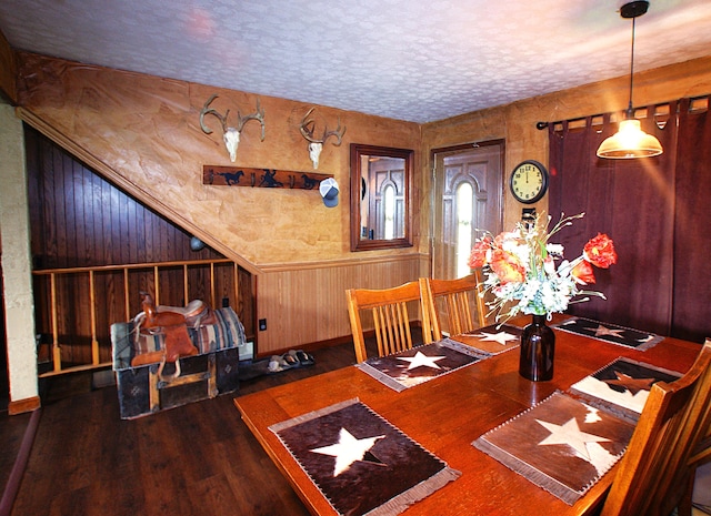 unfurnished dining area with a textured ceiling, dark hardwood / wood-style floors, and wooden walls