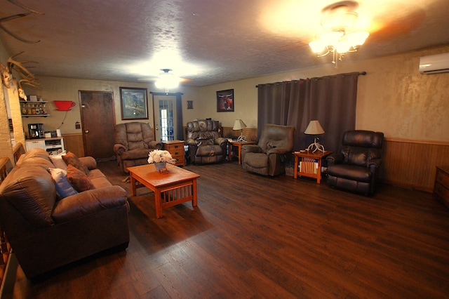 living room featuring a textured ceiling, an AC wall unit, dark wood-type flooring, and wooden walls