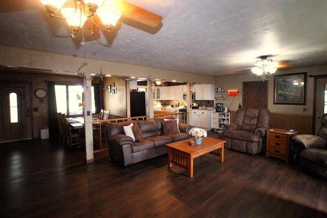 living room with ceiling fan with notable chandelier, a textured ceiling, and dark hardwood / wood-style floors