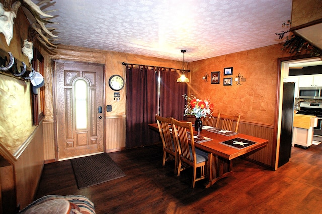 dining room featuring wood walls, dark hardwood / wood-style flooring, and a textured ceiling