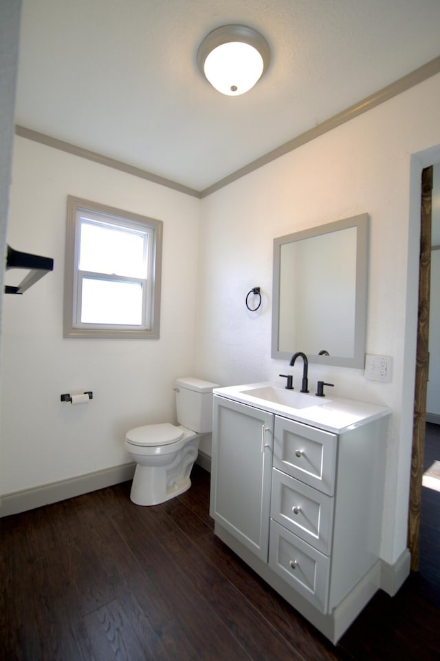 bathroom with vanity, toilet, wood-type flooring, and crown molding