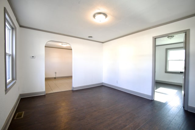 unfurnished room with ornamental molding and dark wood-type flooring