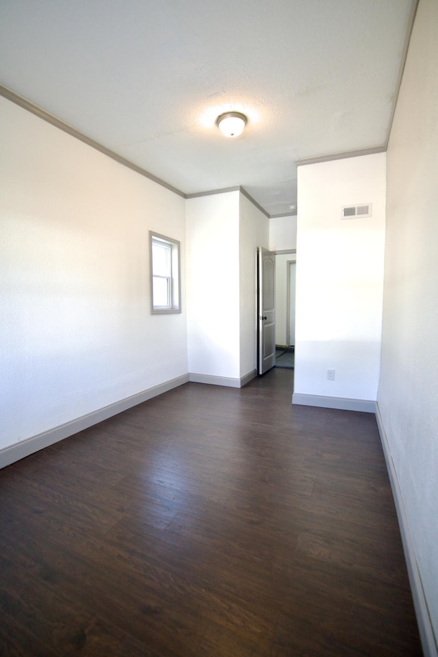 empty room featuring crown molding, dark hardwood / wood-style flooring, and a textured ceiling