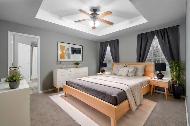 carpeted bedroom featuring a raised ceiling and ceiling fan