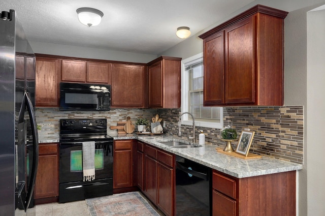 kitchen with black appliances, light stone countertops, sink, and tasteful backsplash