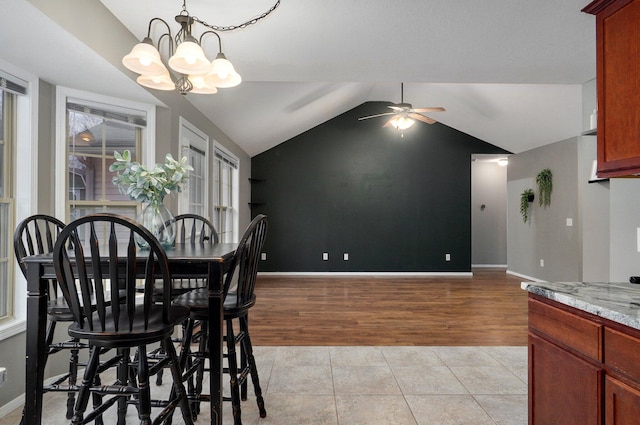 dining room with vaulted ceiling, light tile patterned floors, and ceiling fan with notable chandelier