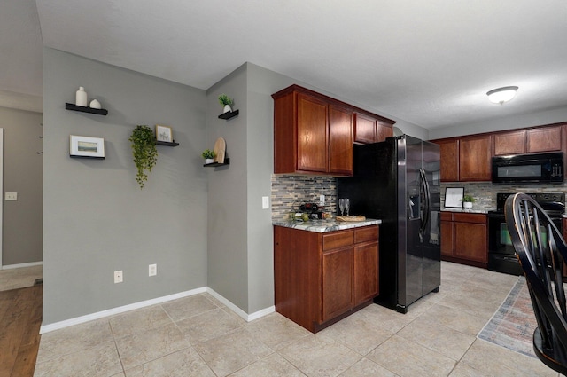 kitchen with light stone countertops, light tile patterned floors, tasteful backsplash, and black appliances