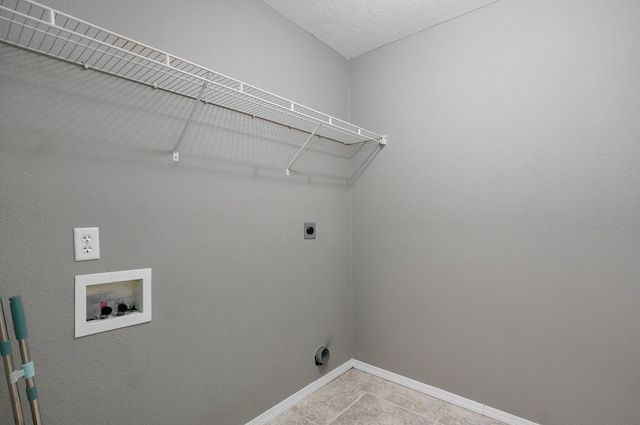 laundry room with electric dryer hookup, hookup for a washing machine, light tile patterned flooring, and a textured ceiling