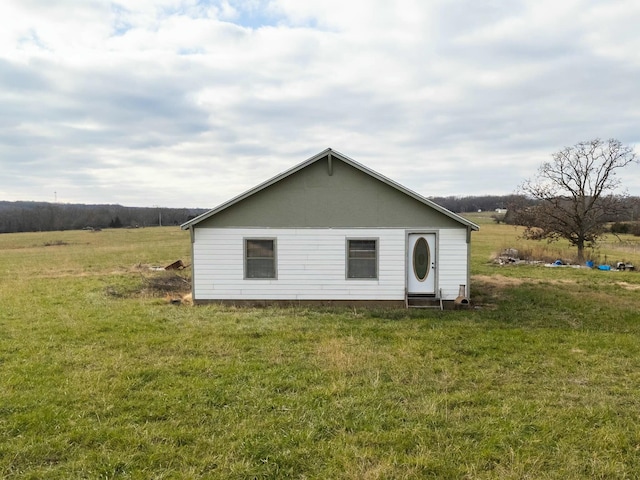 back of house featuring a rural view and a lawn