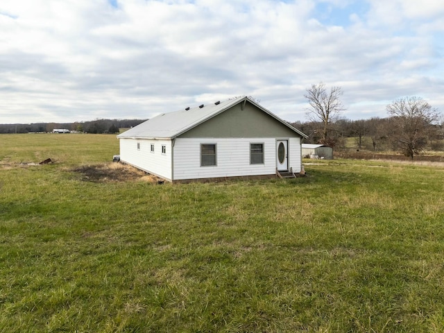 view of side of home featuring a lawn and a rural view