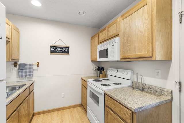 kitchen with light hardwood / wood-style floors, white appliances, and sink