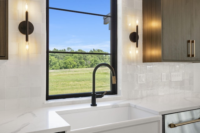 interior details with dishwasher, sink, decorative backsplash, dark brown cabinets, and light stone counters