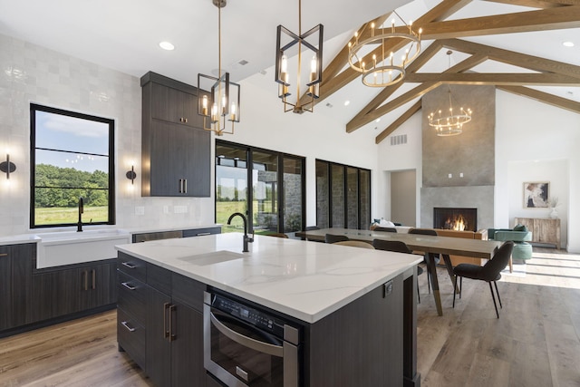 kitchen with beam ceiling, a center island with sink, decorative light fixtures, and sink