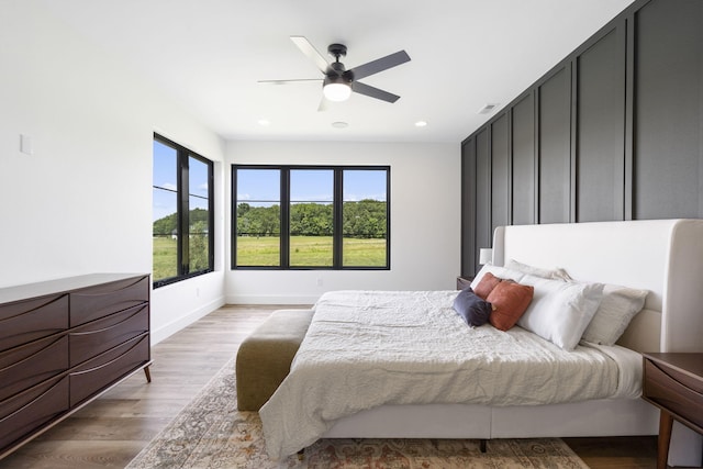 bedroom featuring multiple windows, ceiling fan, and light wood-type flooring