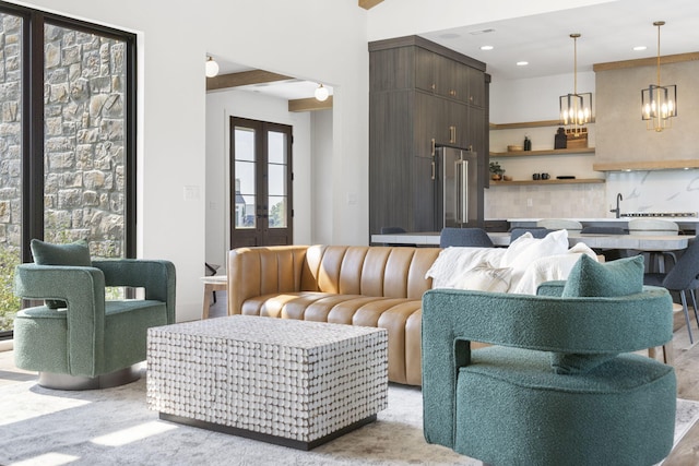 living room featuring beamed ceiling, french doors, and an inviting chandelier