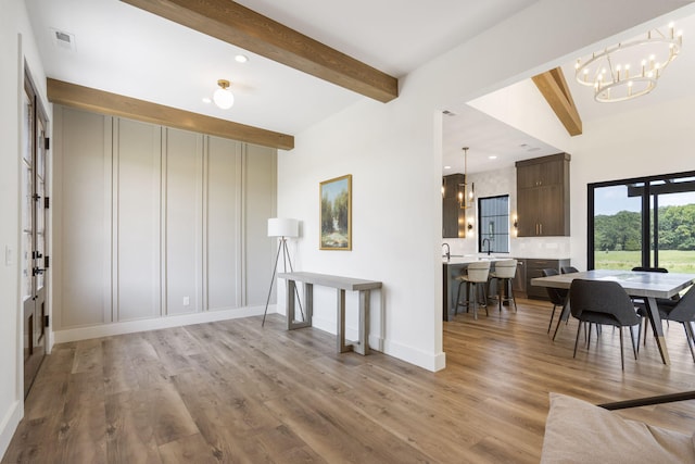 living room with vaulted ceiling with beams, light hardwood / wood-style floors, an inviting chandelier, and sink