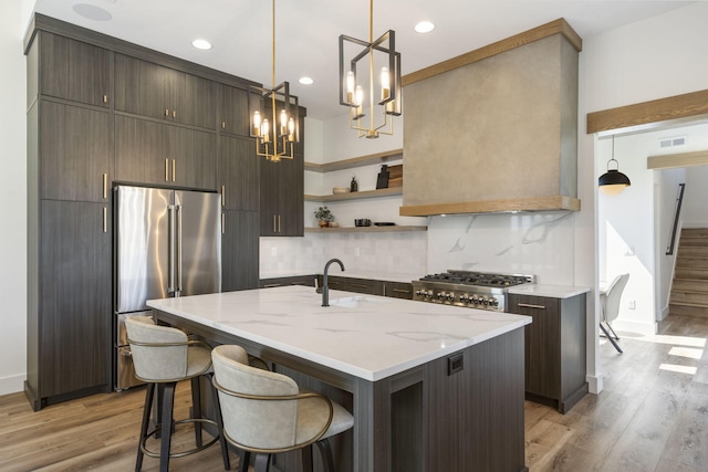 kitchen featuring a kitchen island with sink, sink, light hardwood / wood-style flooring, dark brown cabinetry, and stainless steel appliances