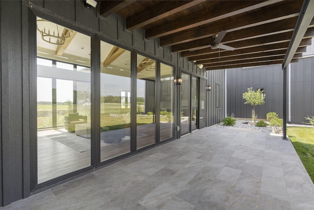 unfurnished sunroom with beamed ceiling and ceiling fan